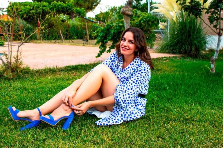 Herrajes de color azul, mujer sentada en césped en jardín, imagen relajante y natural.