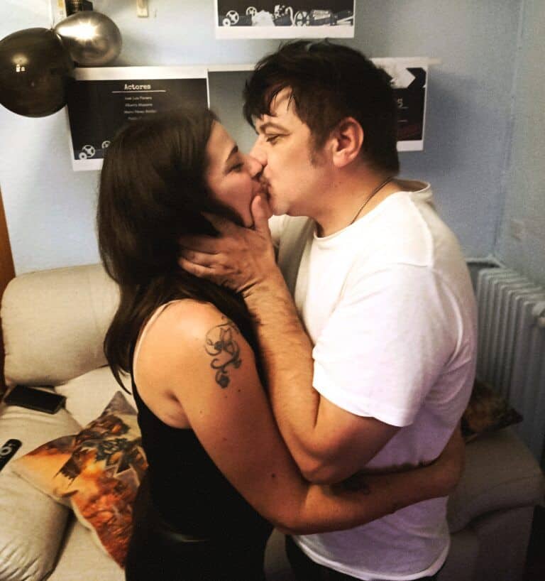 Besos románticos entre pareja en un ambiente acogedor, promoviendo amor y bienestar en Mi Refugio Luminoso.